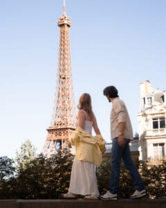 couple walks by eiffel tower in paris