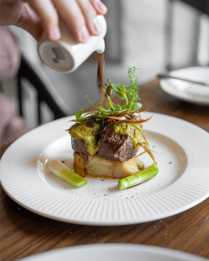 man pours sauce on venison dish