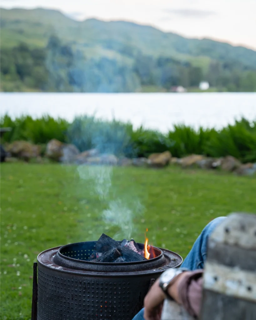 man sits by lake with firepit