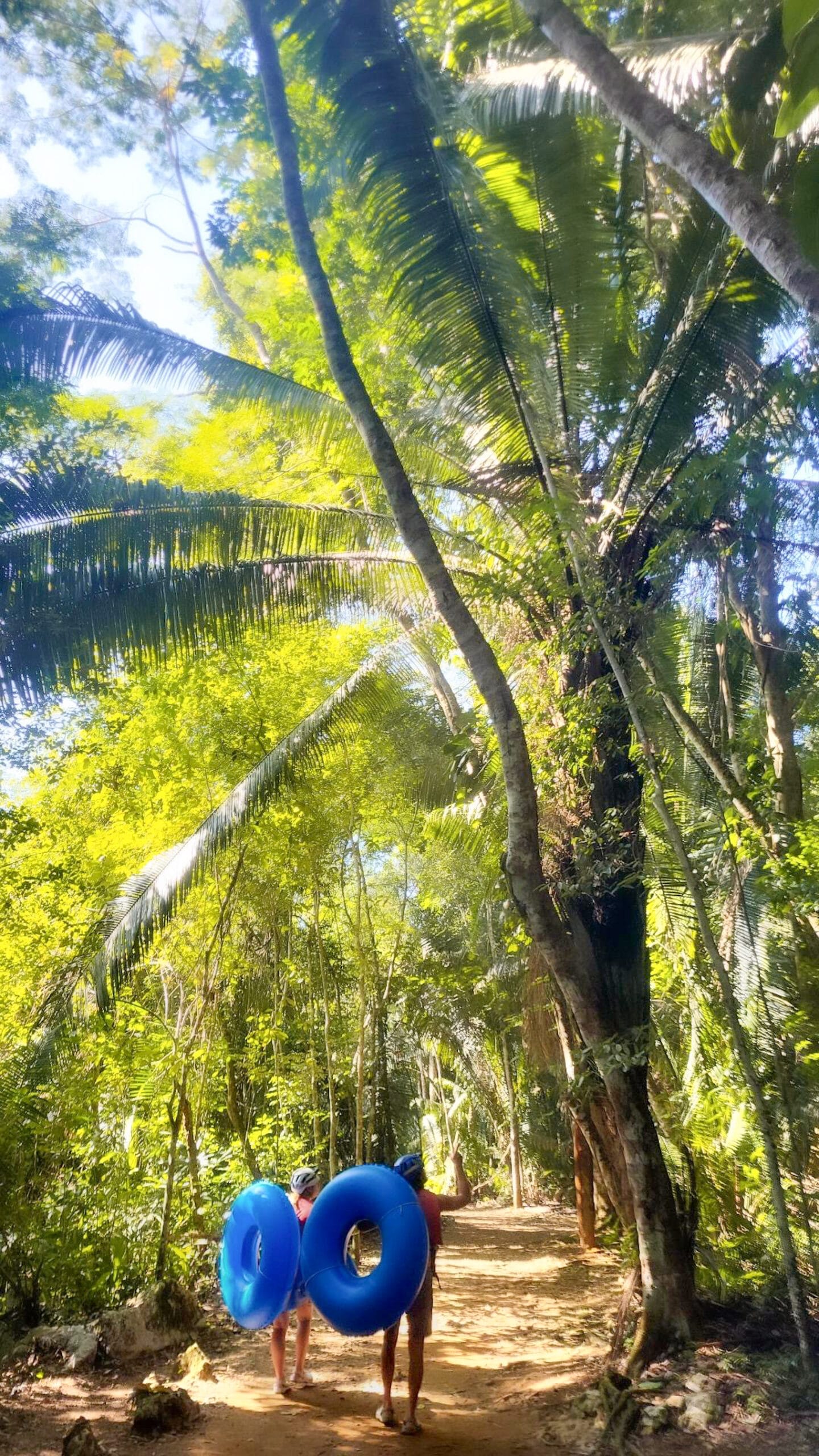 couple walks through jungle in belize with cave tubes