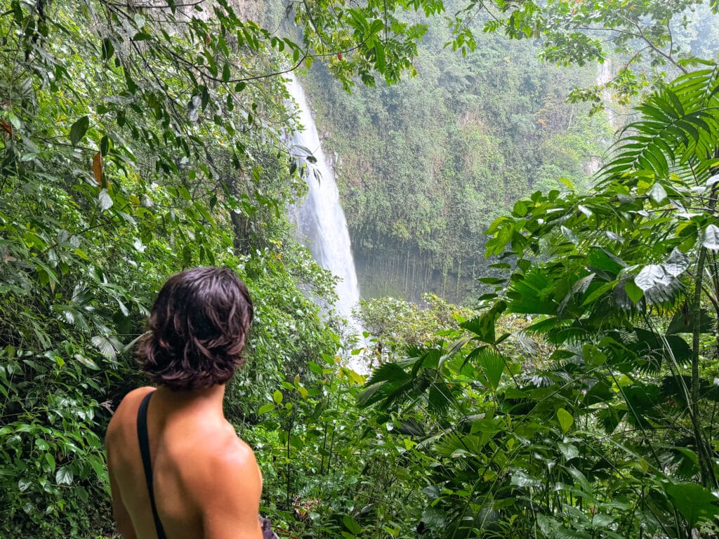 costa rica travel la fortuna waterfall with man looking on from the jungle
