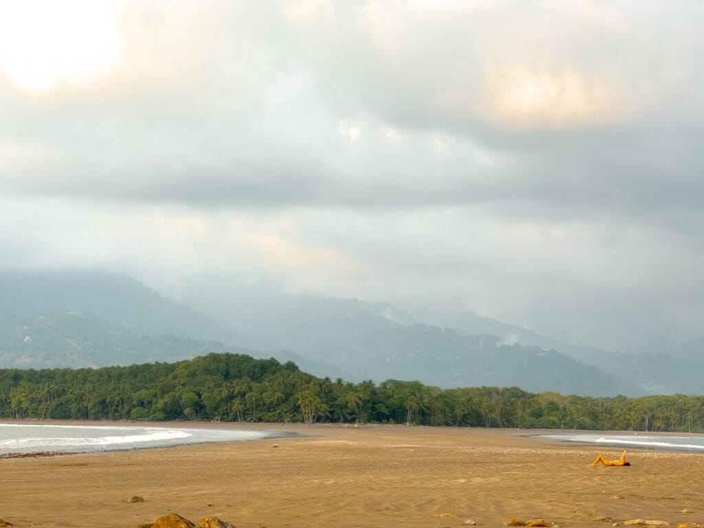 costa rica travel a woman sunbakes in the last golden hour before sunset on the whale tail at Uvita Beach